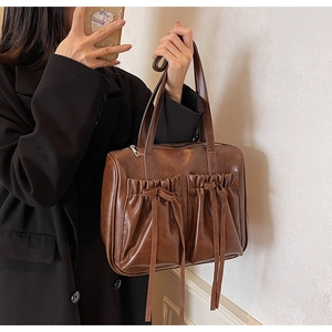 Detail of vintage brown PU leather bag with bow-knot pleats and zip closure