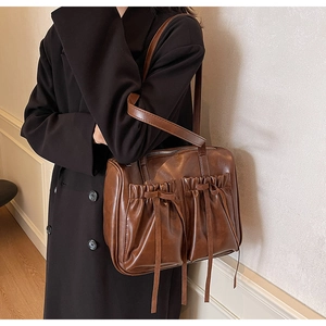 Detail of vintage brown shoulder bag with pleated pockets and decorative bows