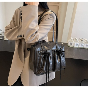Detail of black vintage shoulder bag featuring pleated pockets and decorative ribbons