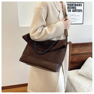 Close-up of brown suede patchwork tote bag with woven handles on model in beige coat