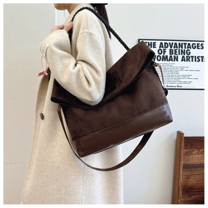 Detail view of large dark brown suede tote bag with woven strap and leather stitching