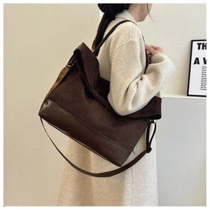 Detail of dark brown tote bag showing mixed textures, woven handle and adjustable strap