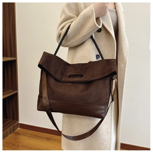 Detail of a large brown suede tote bag with contrast leather trim and twist rope handle