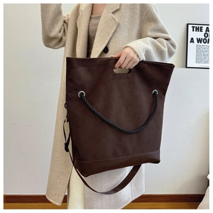 Detail of deep brown tote bag with decorative rope handle and reinforced leather bottom