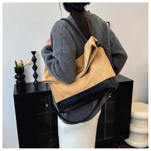 Detail of a large color-block tote bag in yellow suede and black leather texture
