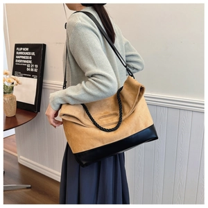 Detail of the camel suede tote bag showing its black leather base and twisted rope handle