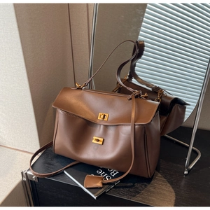 Gros plan détaillé sur un sac cabas en daim marron avec deux fermoirs dorés et fini mat