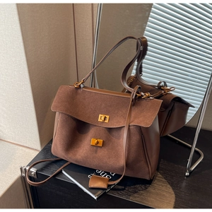 Détail d'un sac à bandoulière en daim marron foncé avec fermoirs rotatifs carrés dorés