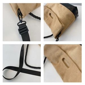 Detail of khaki suede tote bag showing black woven handles and metal strap attachments