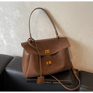 Détail du sac cabas en daim marron foncé avec fermoirs dorés et finitions en cuir lisse
