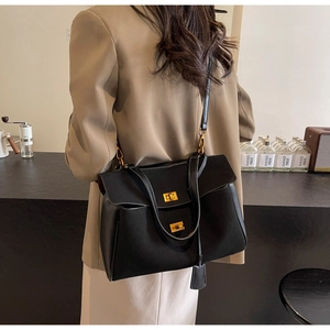 Détail d'un sac cabas en daim noir avec boucle dorée porté par un mannequin
