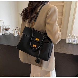 Détail d'un grand sac cabas noir en daim avec ferrures dorées dans un café chic