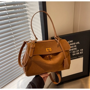 Détail d'un sac à main en daim marron avec fermoir doré et plis latéraux élégants