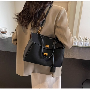 Détail du sac cabas en daim noir avec doubles fermoirs dorés porté à l'épaule pour femme