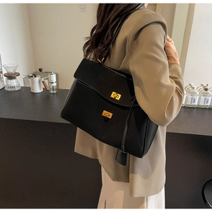Détail d'un grand sac cabas en daim noir avec boucles dorées vintage sur fond minimaliste