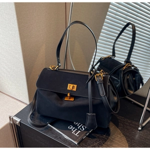 Détail du sac à main noir mat avec fermoir rotatif doré et bandoulière réglable