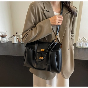 Détail du sac cabas en daim noir avec double fermoir doré et pendentif élégant