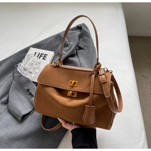 Détail du sac à main en daim marron avec boucles dorées et deux bandoulières sur veste