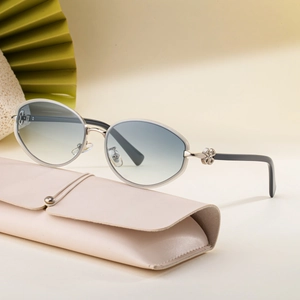 Oval silver sunglasses with light blue gradient lenses and a pink leather case on a fan