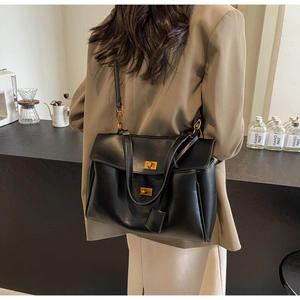Vue détaillée du sac cabas en suédine noire avec ses boucles pivotantes dorées signature
