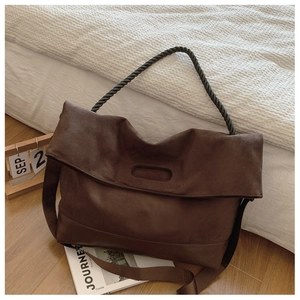 Macro view of dark brown matte tote bag with unique black twisted rope handle detail