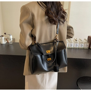 Vue détaillée du grand sac cabas en daim noir porté à l'épaule par un mannequin en extérieur