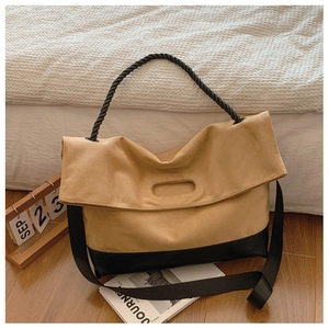 Detail of khaki suede tote bag with black woven handle and contrast stitching texture