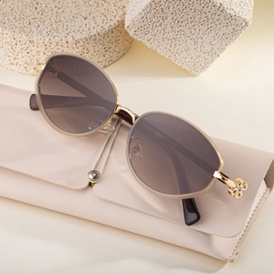 Retro oval sunglasses with gold frame and clover detail on beige leather case