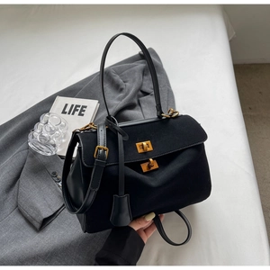 Détail du sac en cuir noir et daim avec deux fermoirs rotatifs dorés et une texture chic