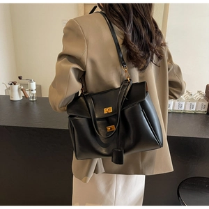 Détail d'un grand sac cabas en daim noir avec verrous dorés et bandoulière réglable