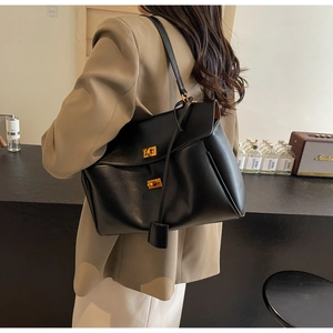 Détail du grand sac cabas noir avec deux fermoirs rotatifs dorés et lanières latérales