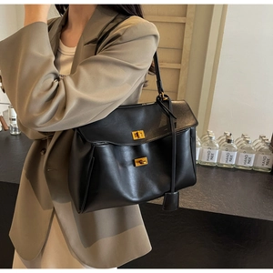 Détail du sac cabas en daim noir avec fermoir doré rotatif et coutures précises
