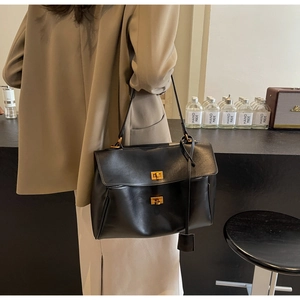 Détail du grand sac cabas en cuir noir avec doubles fermoirs dorés et bandoulière élégante