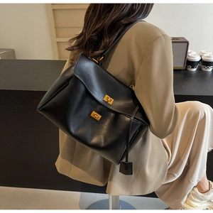 Détails d'un cabas en cuir noir brillant avec double fermoirs dorés et intérieur spacieux