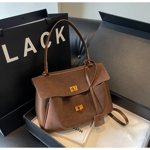 Détail d'un sac cabas en daim marron foncé avec fermoirs métalliques dans un coffret cadeau
