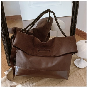 Detail of a brown tote bag with woven rope handles and suede-leather patchwork design