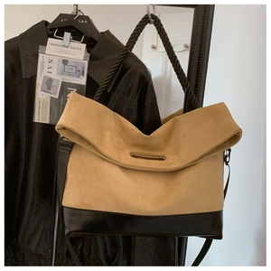 Detail of the large tote bag showing suede and leather textures with woven strap