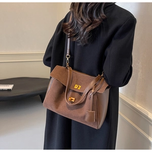 Détails du sac cabas en daim marron avec deux fermoirs rotatifs dorés et une bandoulière