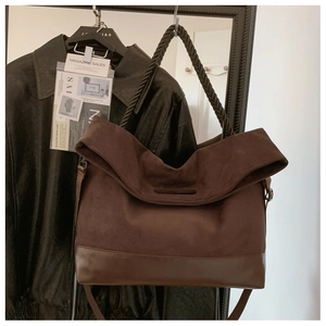 Detail of dark brown suede and leather tote bag featuring a woven handle and slouchy design