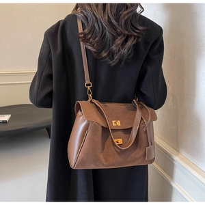 Détails de texture suède et cuir lisse sur sac marron avec fermoirs métalliques dorés