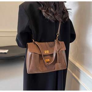 Détail du daim marron et des coutures en cuir avec un fermoir doré sur le sac à main