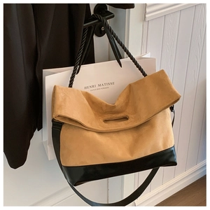 Detail of two-tone tote bag with mustard suede, twisted handle and flat black leather strap