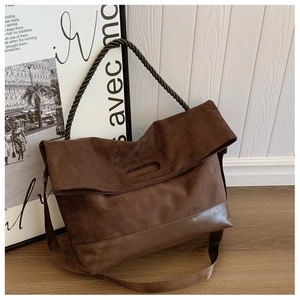 Detail of vintage brown suede tote bag featuring braided handles and durable leather base