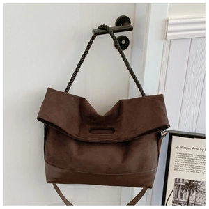 Detail of dark brown suede tote bag featuring unique spiral rope handle and long strap