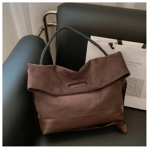 Detail view of brown suede and leather tote bag with braided black handle