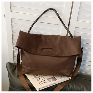 Detailed view of the dark brown suede tote bag with woven handles and a long shoulder strap