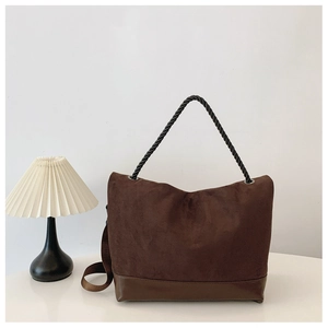 Detail of a brown suede tote bag with black rope handle and smooth leather base