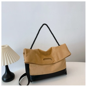 Detail of khaki suede tote bag featuring black twisted rope handles and polished leather base