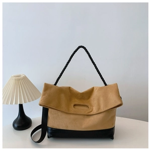 Detail of two-tone tote bag featuring yellow suede texture and black leather bottom