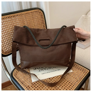 Detail of suede tote bag featuring twisted rope handles and leather patchwork base